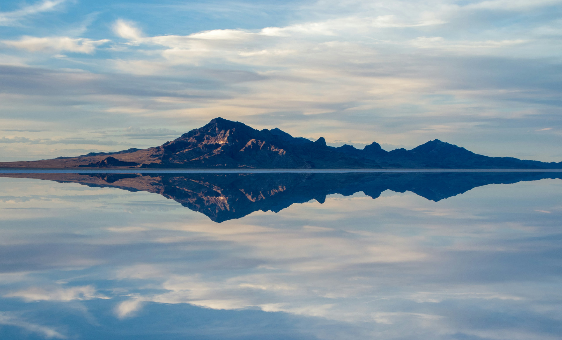 A jagged mountain range mirrored perfectly in still water at dawn