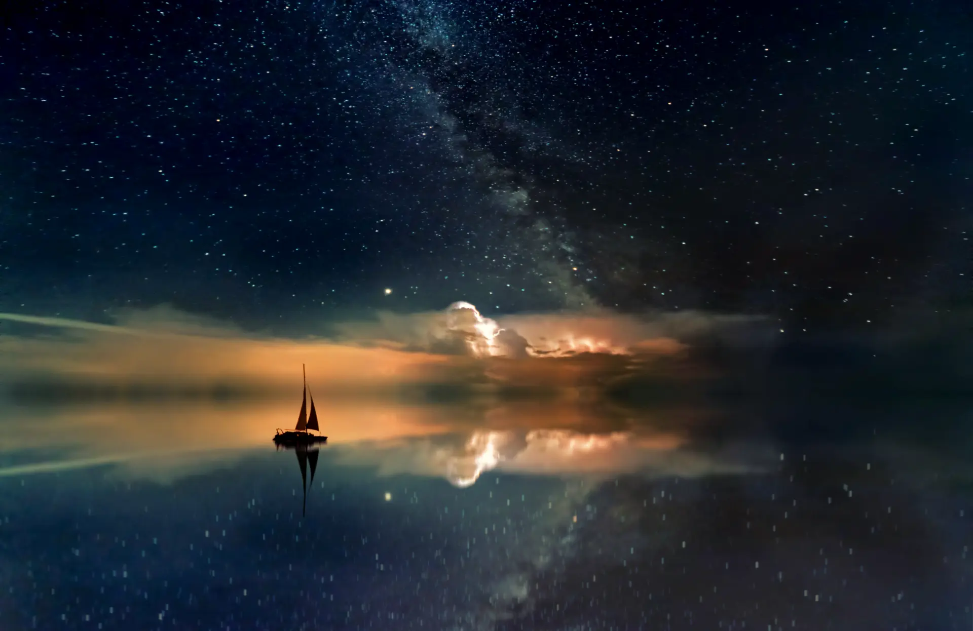 A sailboat resting on still water beneath a starlit sky